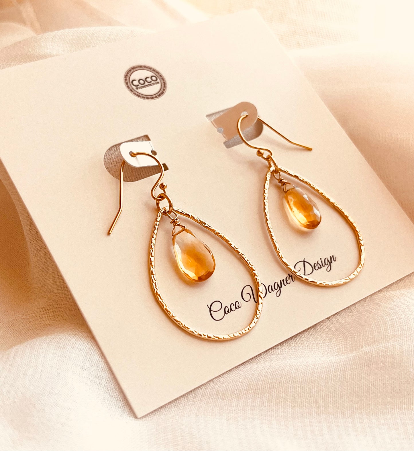 Elegant and lightweight, these handcrafted earrings feature warm yellow teardrop gemstones suspended inside textured 14k gold-filled teardrop hoops. Each stone catches the light with a soft shimmer, adding a refined pop of color to any outfit. The delicate hammered finish on the hoops adds subtle detail and dimension, perfect for both everyday wear and special occasions. Made with care and precision, these earrings combine timeless design with artisan craftsmanship.