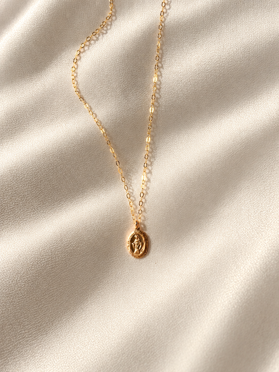 Minimalist gold filled Virgin Mary medal necklace featuring a small oval Catholic pendant and delicate gold chain.