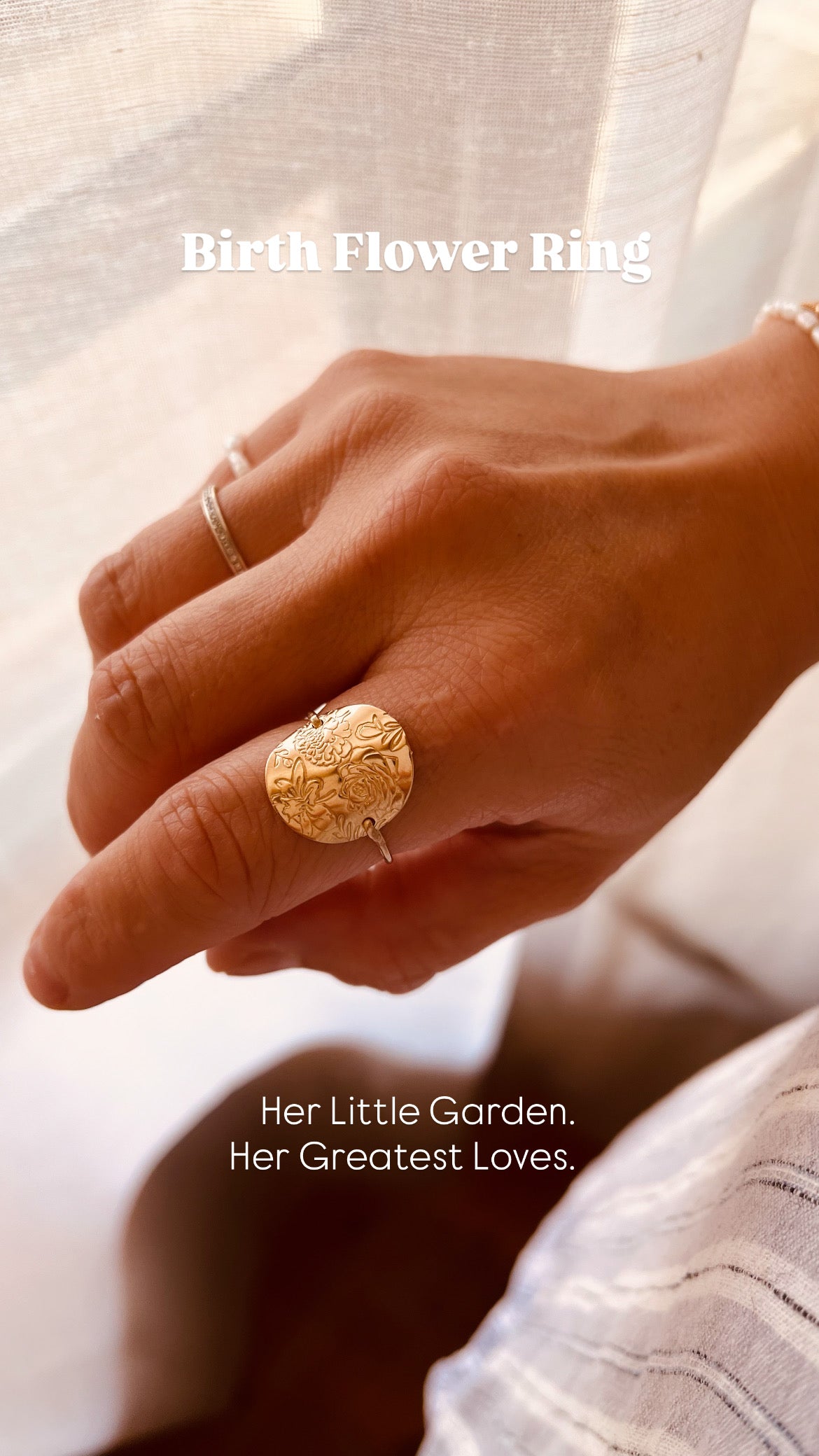 A close-up of a hand wearing a gold ring with a floral, garden-like embossed design. The image has text overlays reading 'Birth Flower Ring' and 'Her Little Garden.