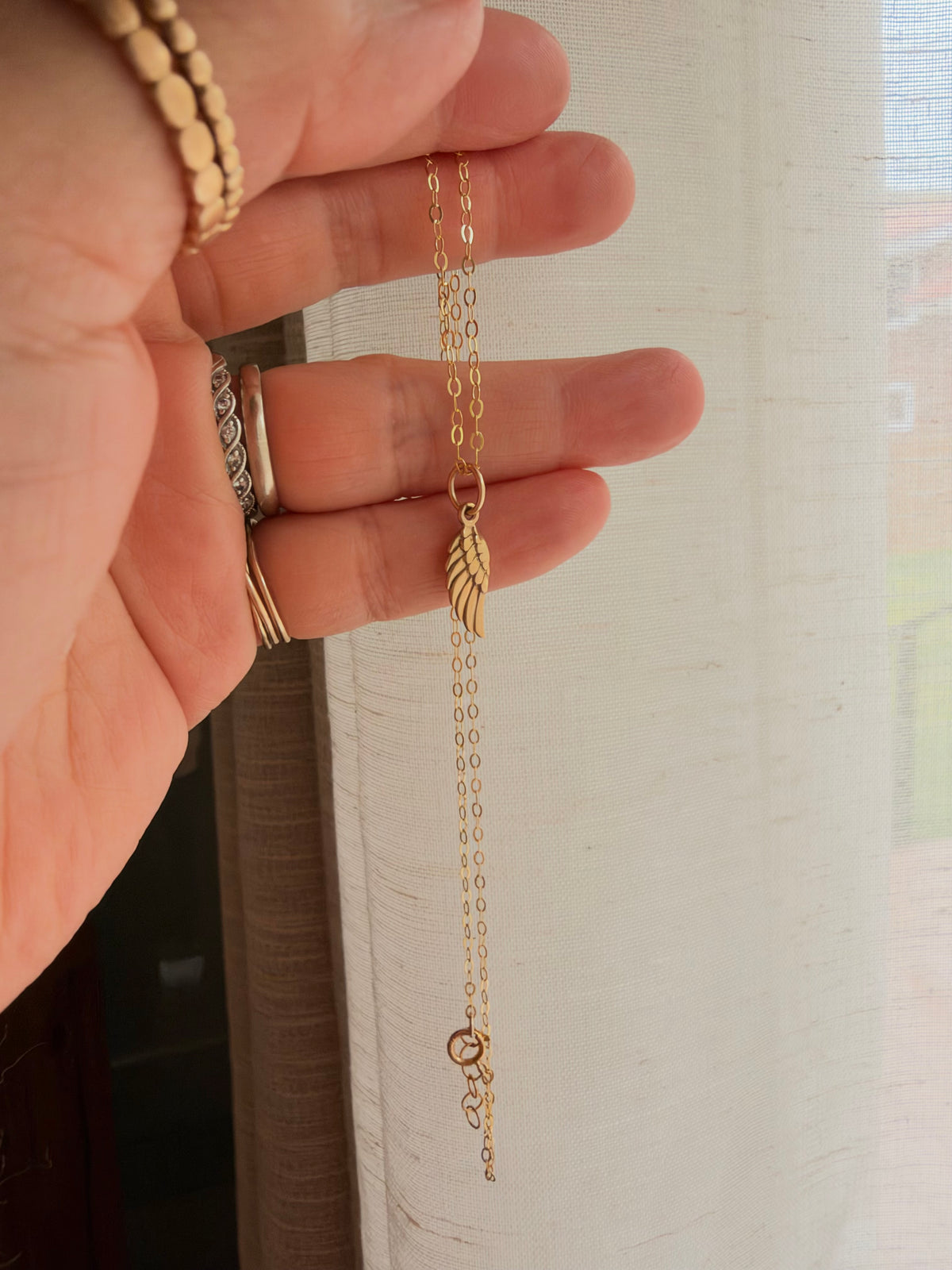Tiny bronze angel wing pendant on 14K gold filled chain, showing its delicate 16mm size wing charm 