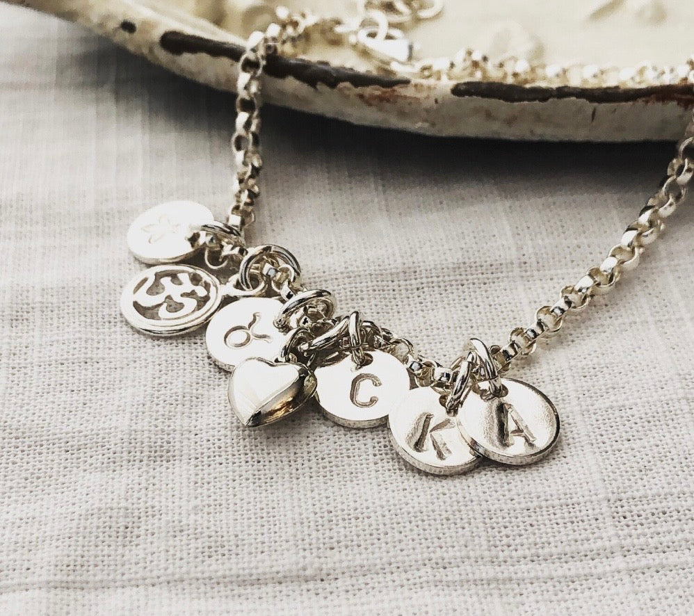 Personalized sterling silver initial charm bracelet with hand stamped discs and charms

Sterling silver personalized bracelet with initial, heart, cross, paw and OM charms