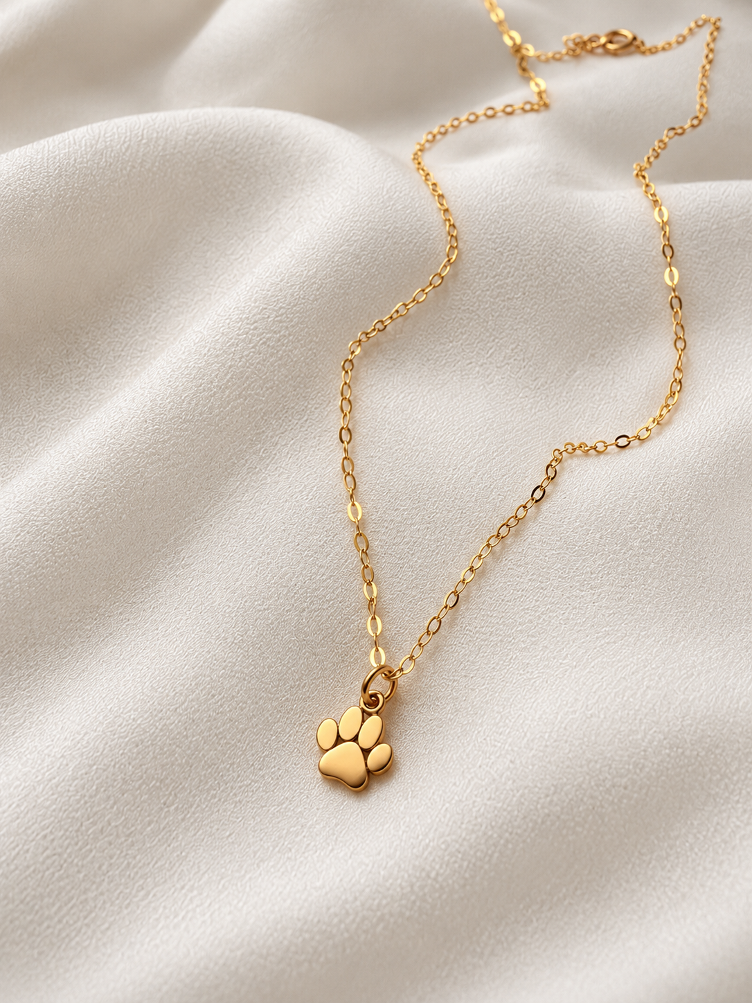 Tiny 10mm bronze paw print charm necklace with delicate 14K gold filled chain, shown in hand for size reference.