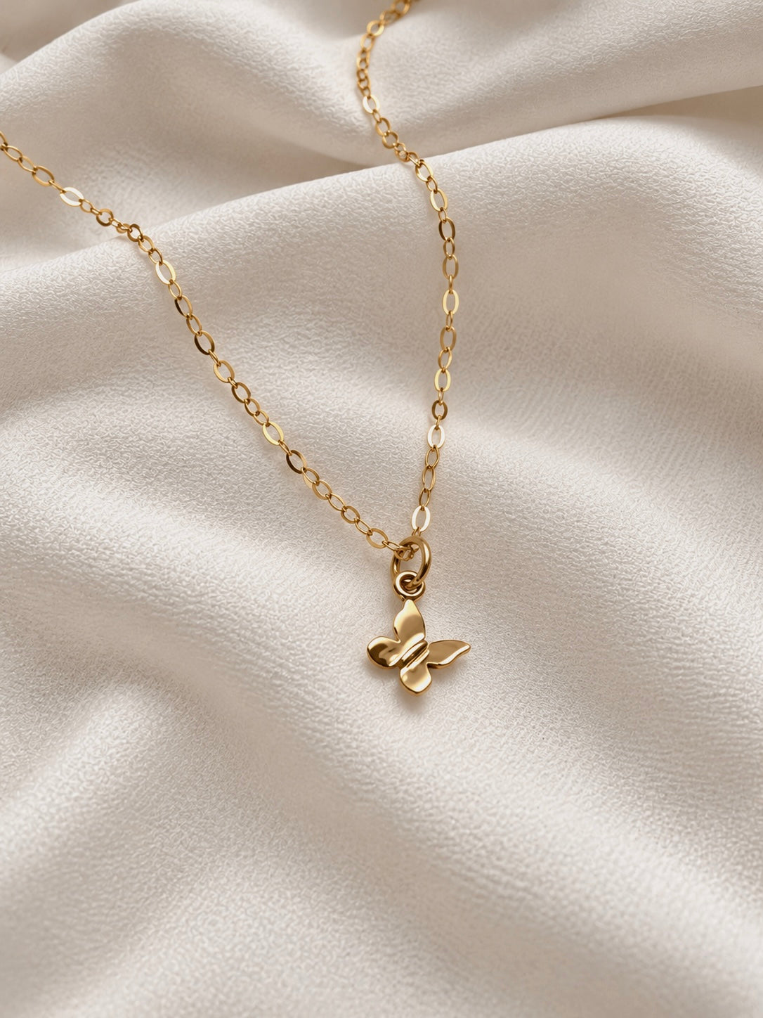 Dainty 14K gold filled chain necklace with tiny 9mm bronze butterfly charm on ivory fabric, handmade everyday jewelry.