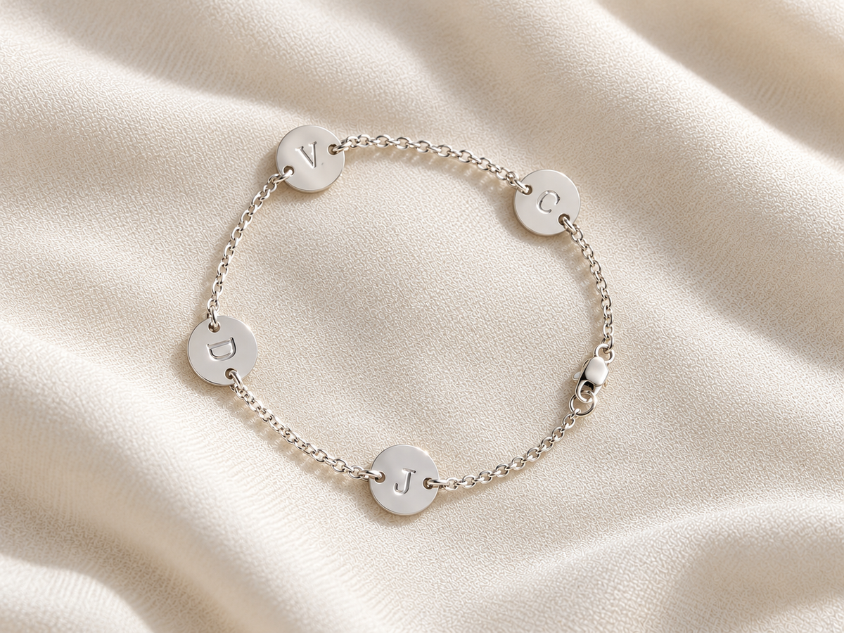 Sterling silver personalized family initial bracelet with four engraved letter discs, lightweight custom size bracelet for grandma.