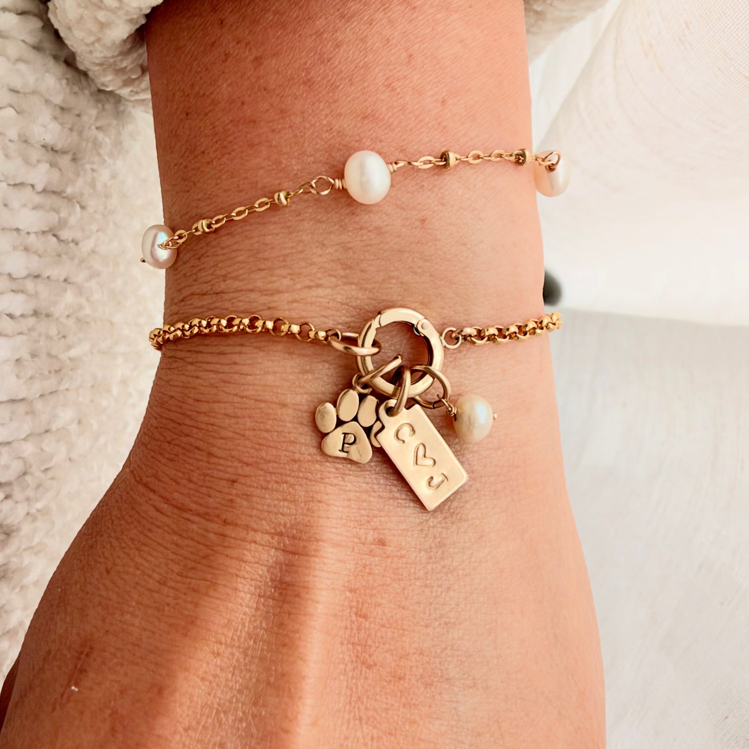personalized 14K gold-filled charm holder bracelet features her pearl birthstone, a paw print with her fur baby’s initial, and meaningful charms chosen just for her.
