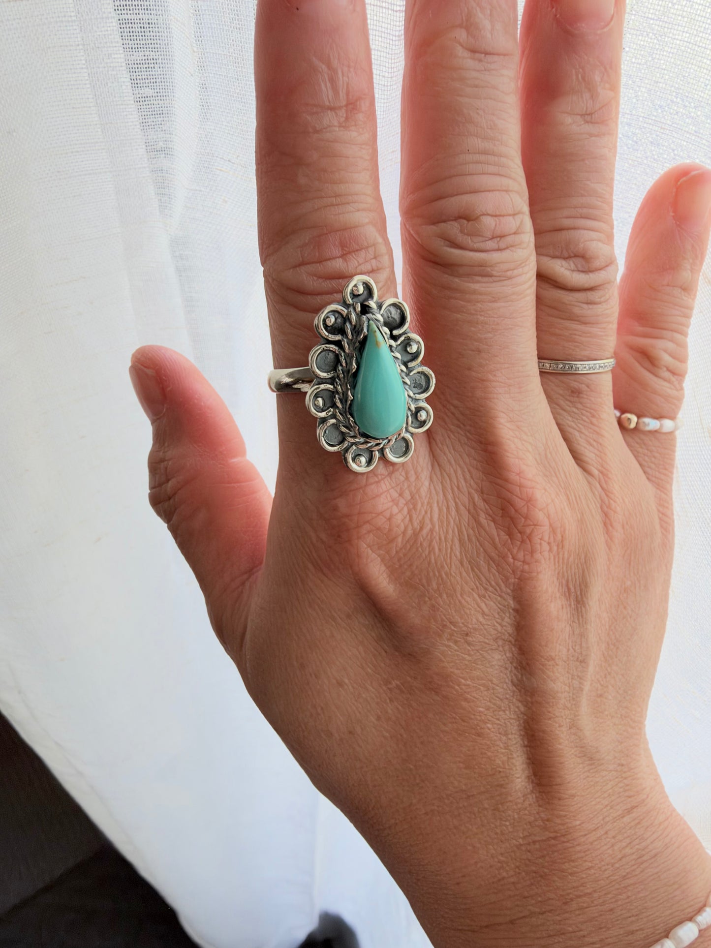 This statement ring features a teardrop-shaped turquoise stone surrounded by detailed oxidized sterling silver scrollwork. Bold yet easy to wear, it adds the perfect touch of rustic Western style to any outfit.