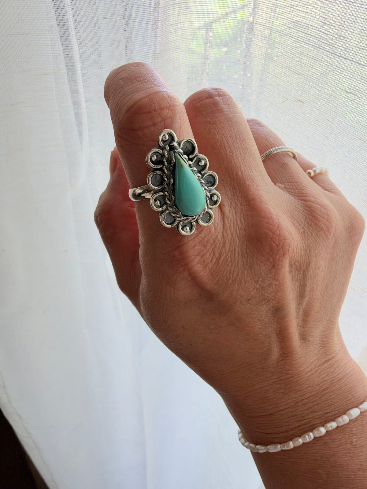 This statement ring features a teardrop-shaped turquoise stone surrounded by detailed oxidized sterling silver scrollwork. 