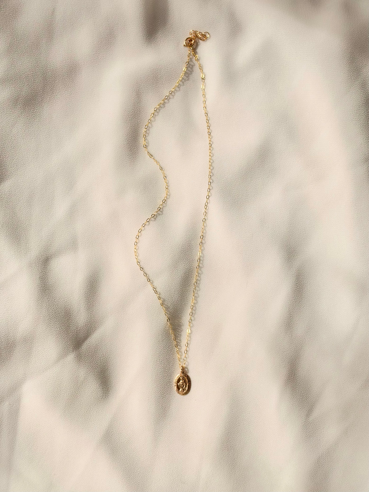 A dainty 14K Gold Filled Virgin Mary Necklace with a tiny 9x13mm double-sided oval medal. Lightweight, timeless Catholic jewelry for everyday wear.