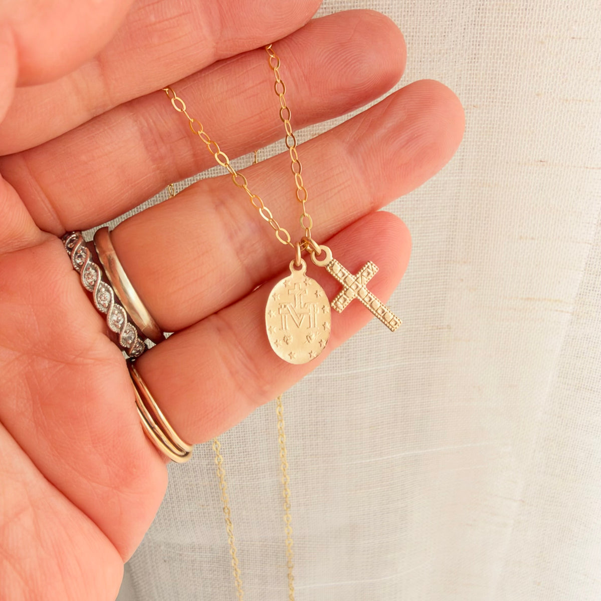 Back view of double-sided Virgin Mary medal and cross charms on a delicate 14K gold filled religious necklace.