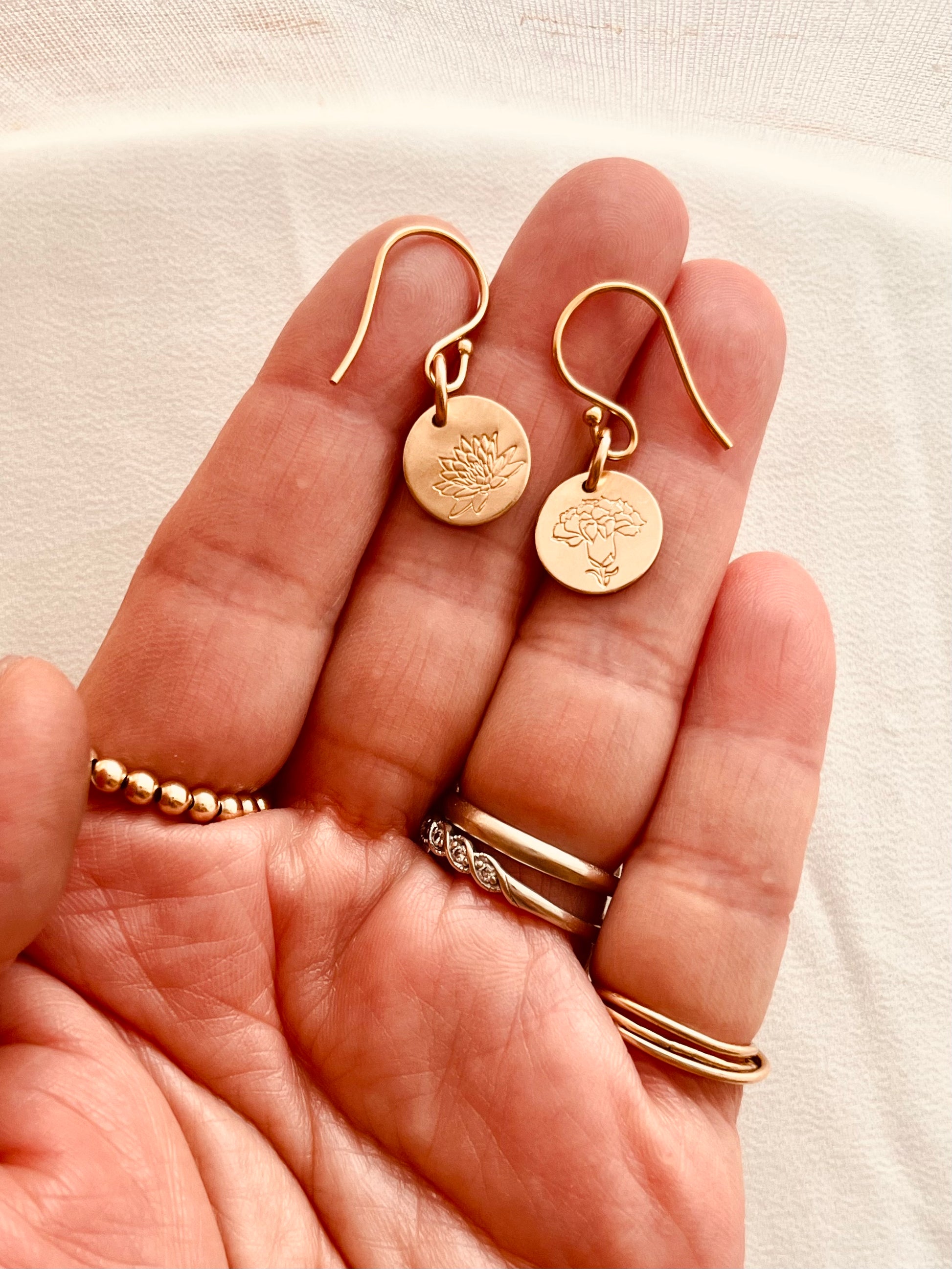 Personalized birth flower drop earrings shown in hand for size reference